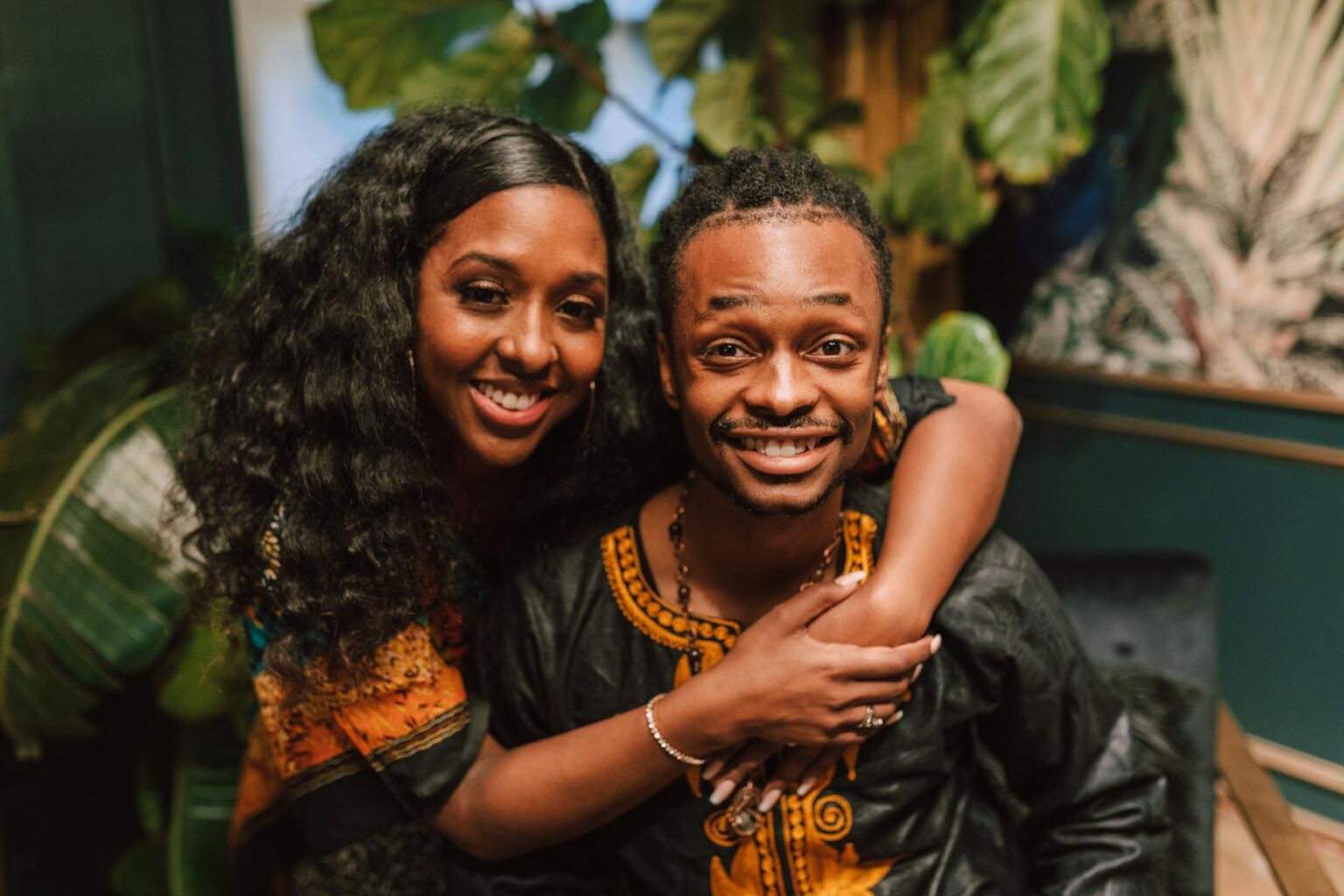 smiling couple in black and orange traditional wear