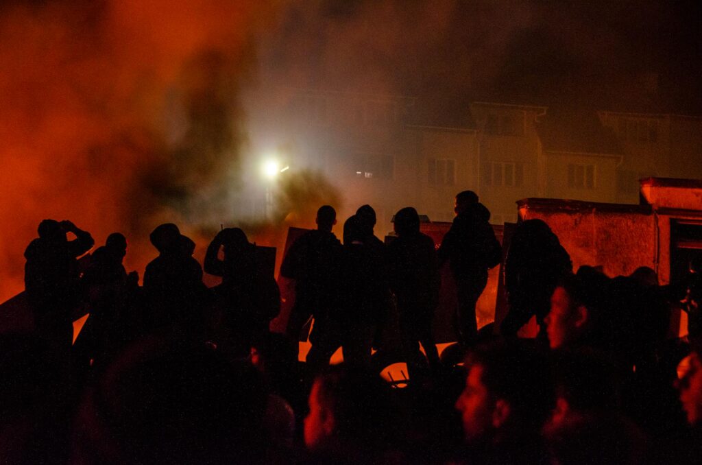 silhouette of people standing near the burning building