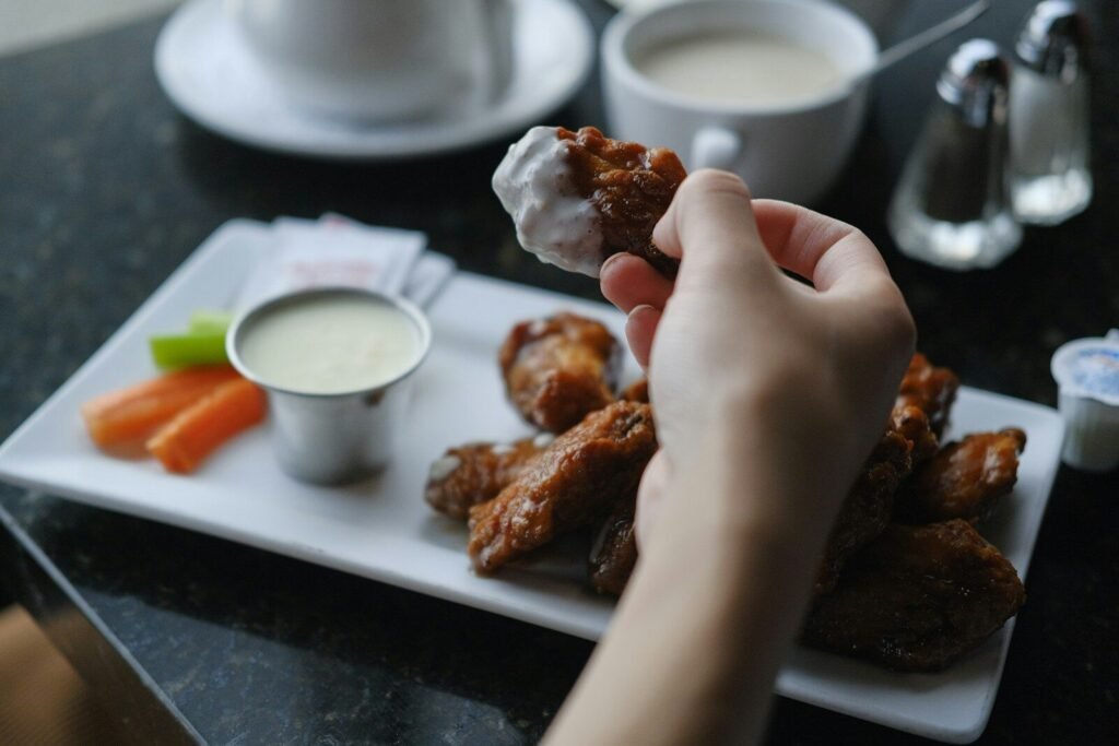 Hand dipping a buffalo chicken wing into ranch sauce